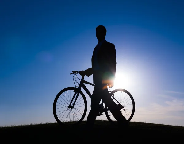 Zakenman met fiets op de heuvel bij zonsopgang — Stockfoto