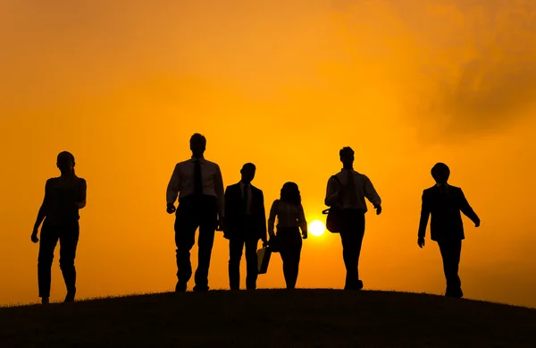 Geschäftsleute gehen bei Sonnenuntergang auf dem Hügel spazieren — Stockfoto