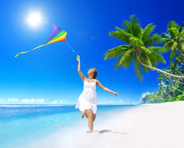 Vrouw met vliegende kite op strand — Stockfoto