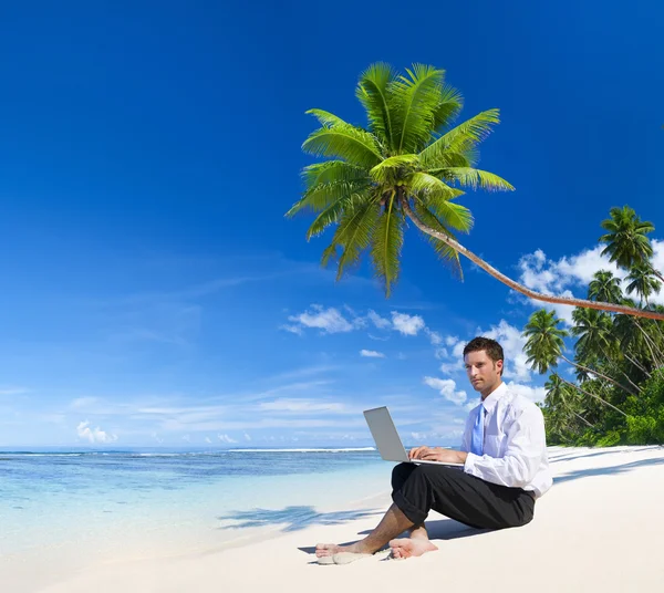 Homme d'affaires travaillant sur ordinateur portable sur la plage — Photo