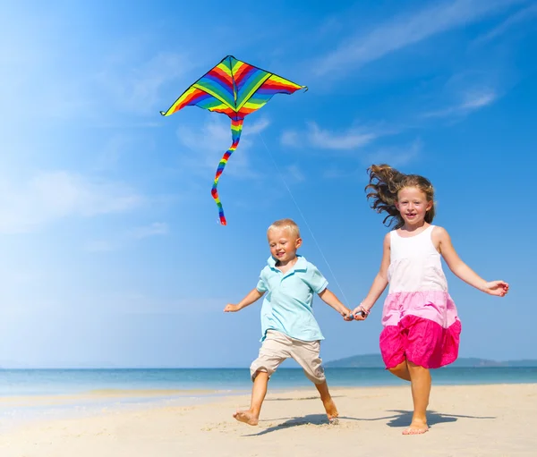 Schwester und Bruder spielen mit Drachen am Strand — Stockfoto