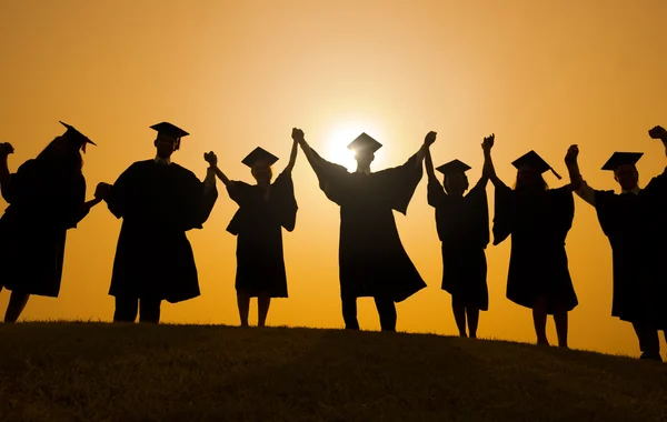 Gente celebrando la graduación al atardecer — Foto de Stock