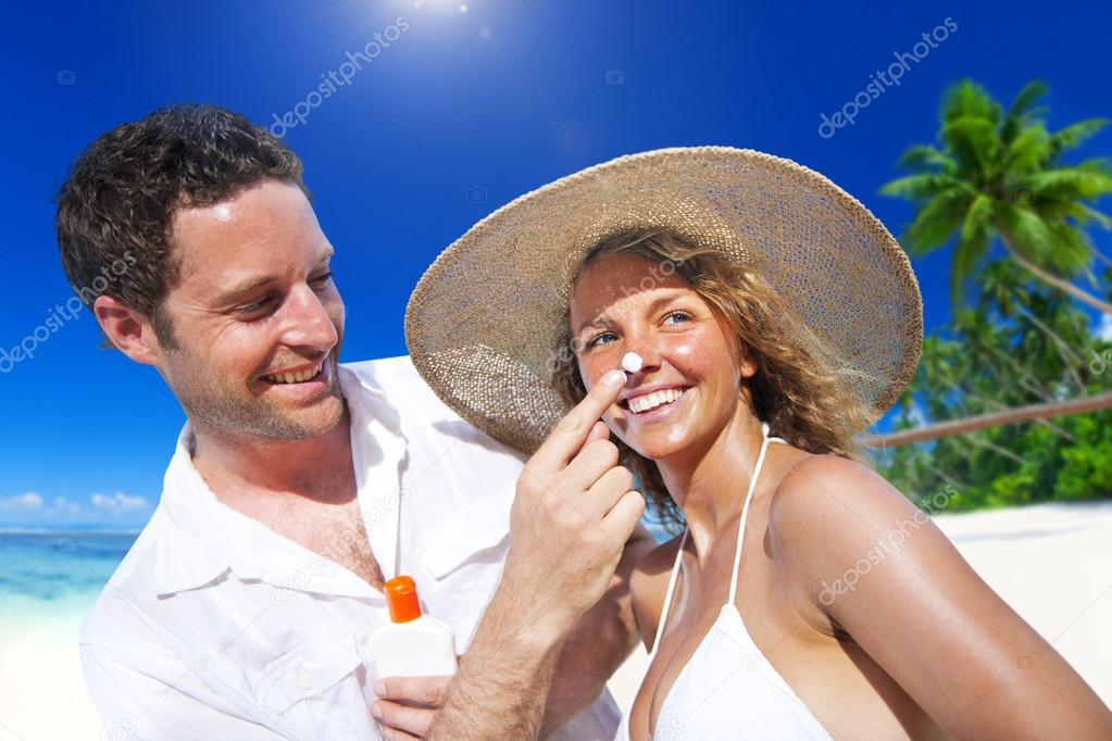 Couple applying sun protection on beach