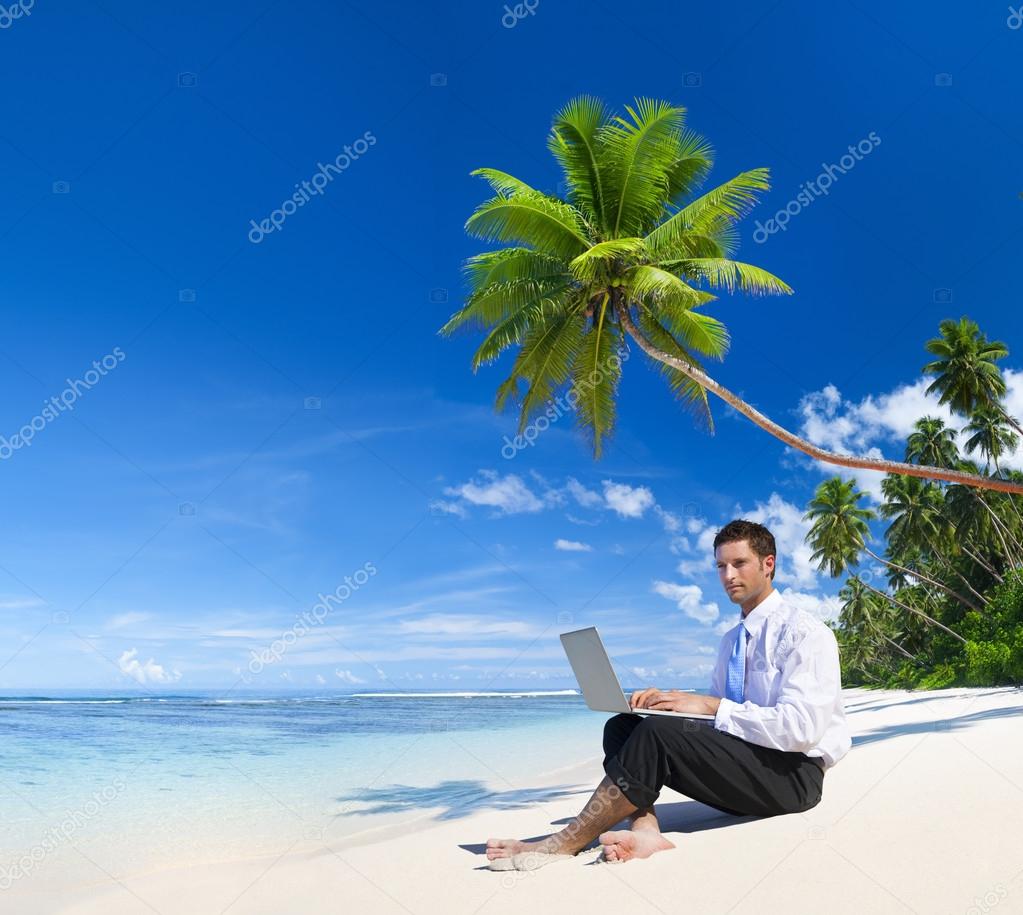 Businessman working on laptop on beach