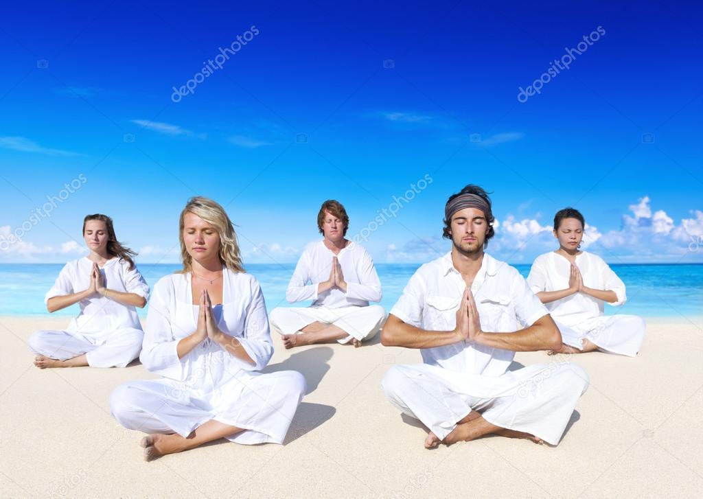 People performing yoga on beach