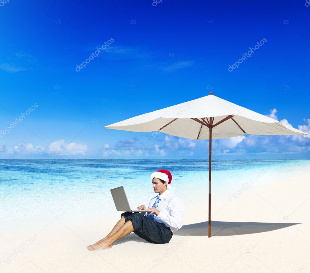 Businessman in Santa Hat Working in a Beach