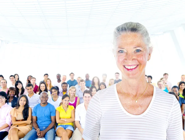 Senior woman standing out from crowd — Stock Photo, Image