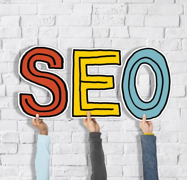 Manos sosteniendo la letra SEO — Foto de Stock