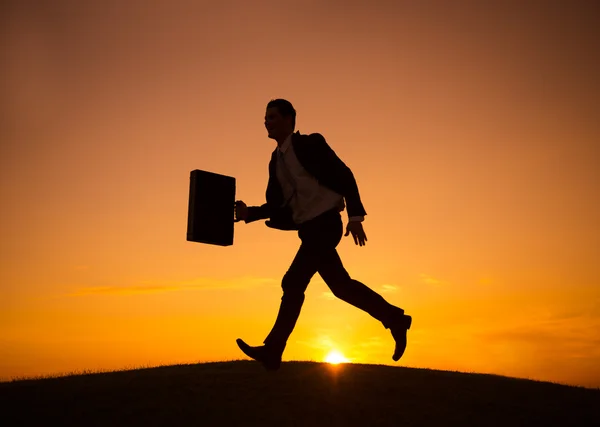 Homme d'affaires courant devant le coucher du soleil — Photo