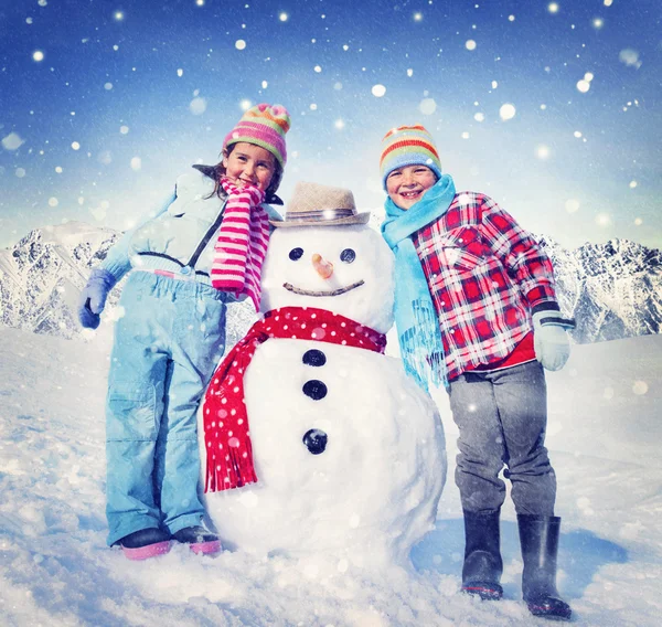 Девочка и мальчик со снеговиком — стоковое фото