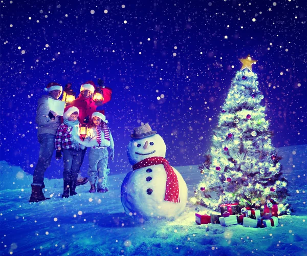 Aile ve Noel ağacı yakınındaki kardan adam