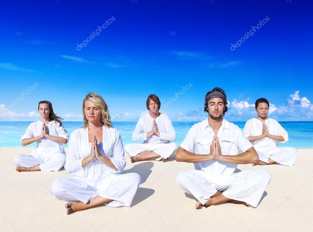 People performing yoga on beach