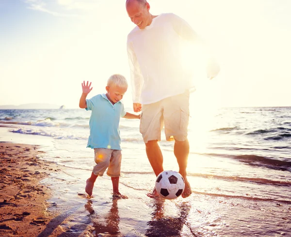 Far och son leker med bollen på stranden — Stockfoto
