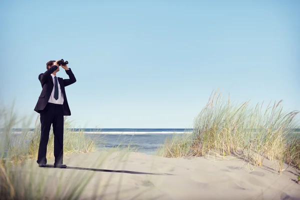 Affärsman med kikare på stranden — Stockfoto