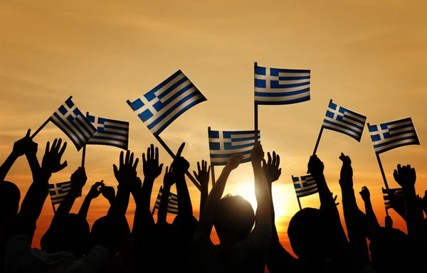 Silhuetas de pessoas segurando as bandeiras da Grécia — Fotografia de Stock