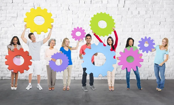 Diversidade Pessoas segurando engrenagens — Fotografia de Stock