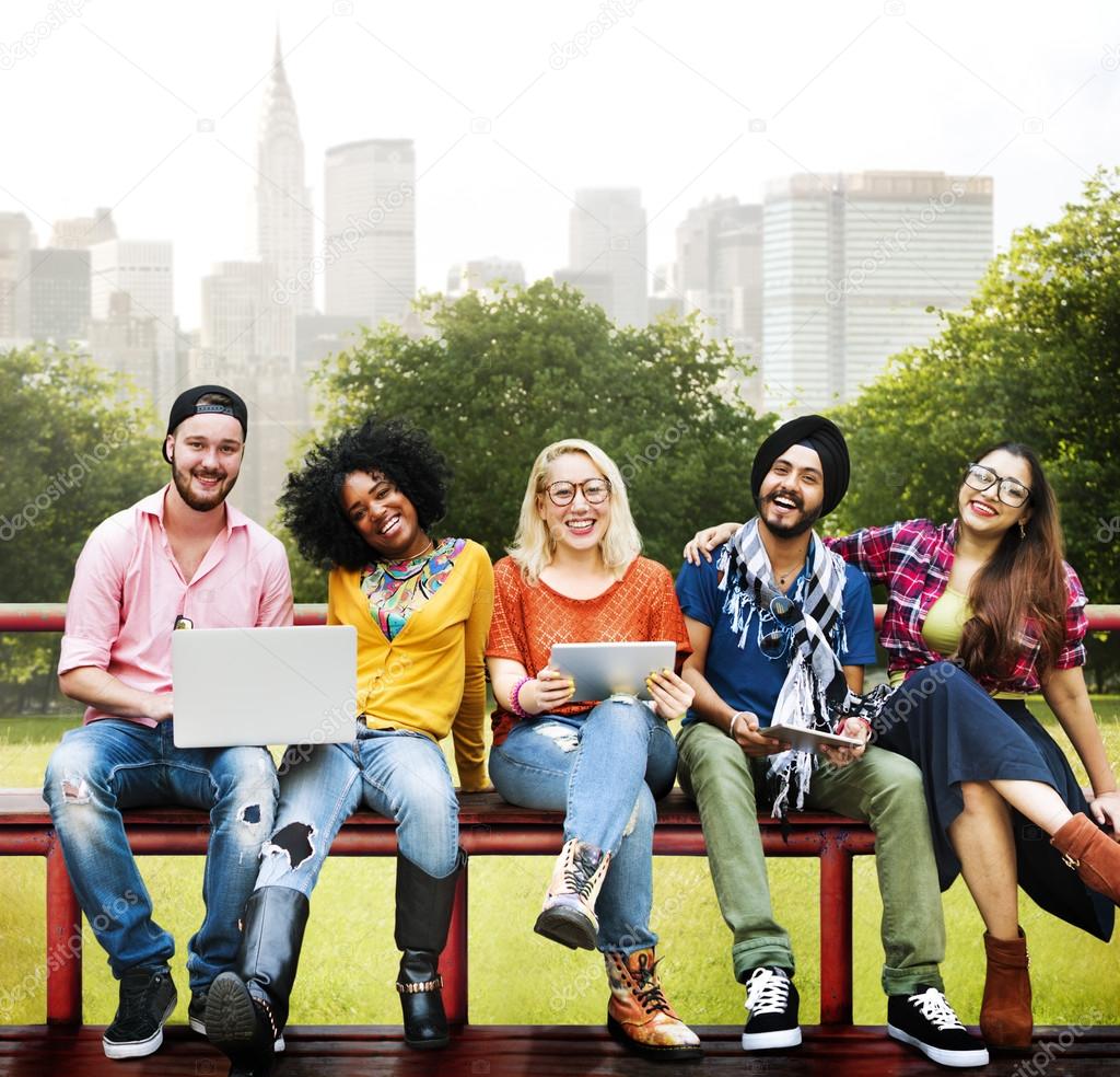 friends sitting on bench with laptop computers
