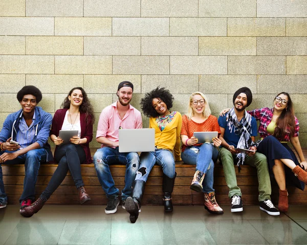 Amigos felices sentados en el banco con el ordenador portátil —  Fotos de Stock