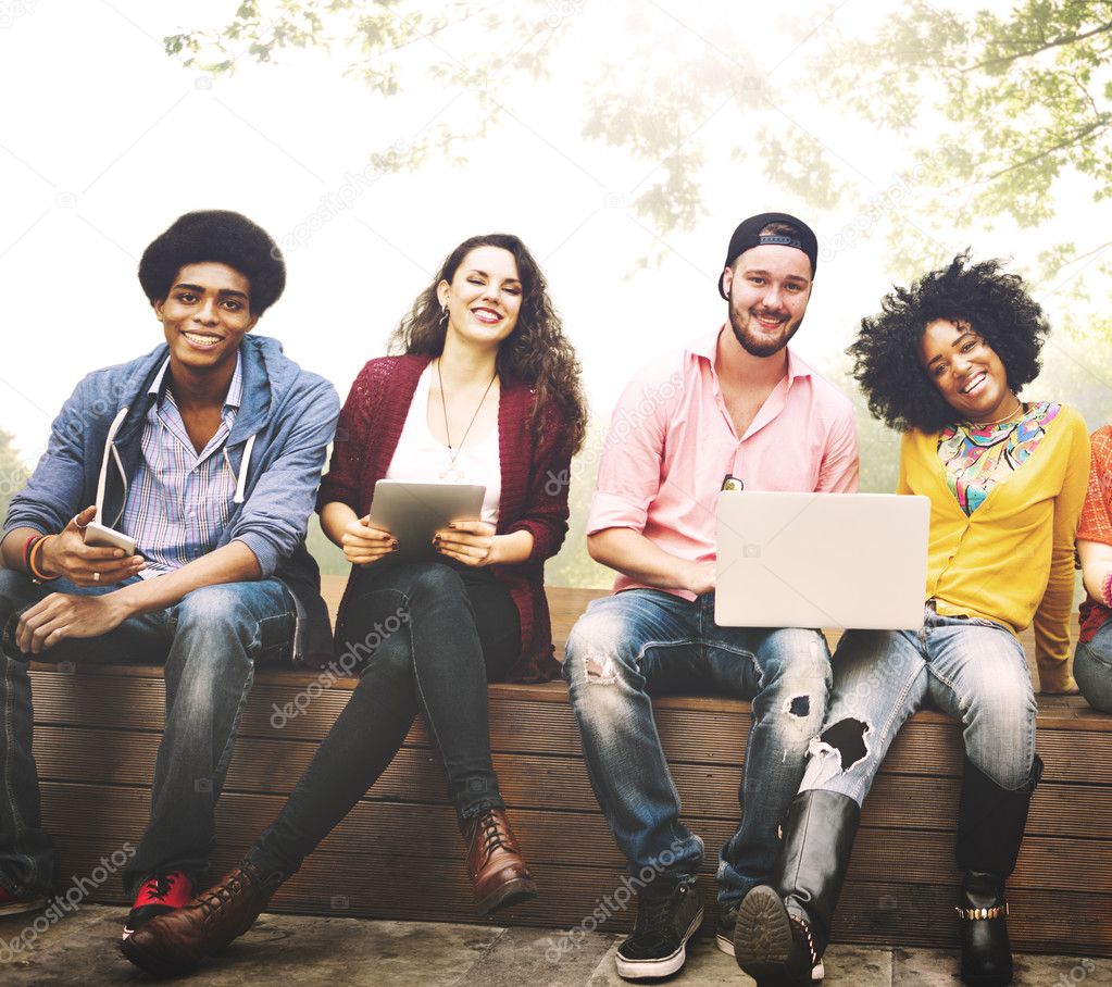 happy friends sitting on bench with laptop