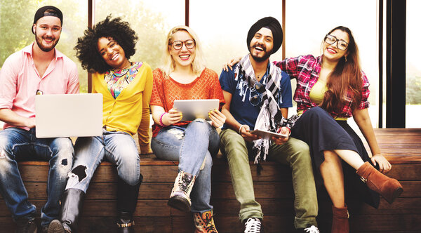 счастливые друзья сидят на скамейке с ноутбуком
