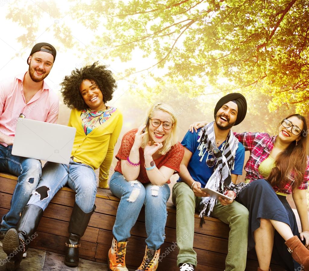 happy friends sitting on bench with laptop