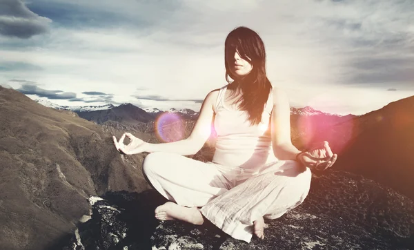 Mujer sentada meditando en las montañas — Foto de Stock