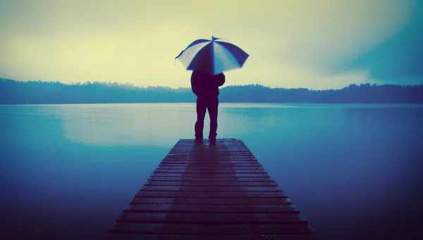 Чоловік тримає парасольку на озері — стокове фото