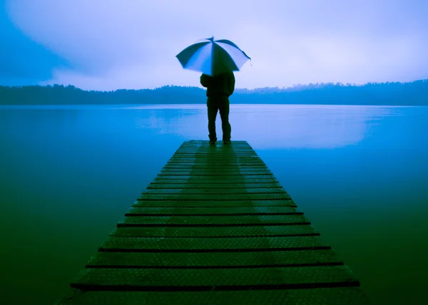 Homem segurando um guarda-chuva no lago — Fotografia de Stock