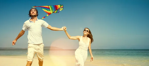 Pareja jugando con cometa, Relajarse en el concepto de playa — Foto de Stock