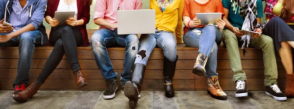 Amigos felizes sentados no banco com laptop — Fotografia de Stock