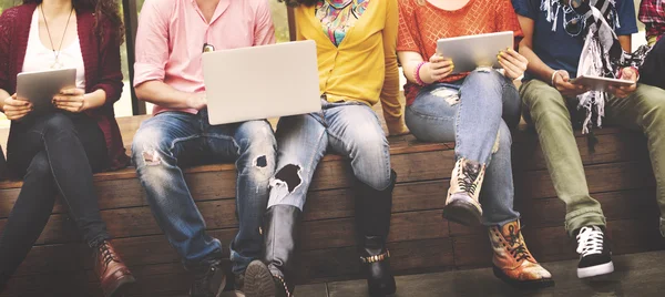 Счастливые друзья сидят на скамейке с ноутбуком — стоковое фото