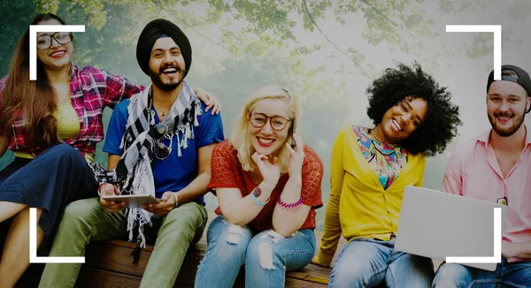 Freunde sitzen auf Bank mit drahtlosen Geräten — Stockfoto