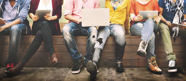 Amigos felizes sentados no banco com laptop — Fotografia de Stock