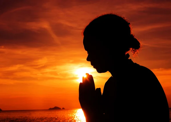 Молода жінка молиться на заході сонця — стокове фото