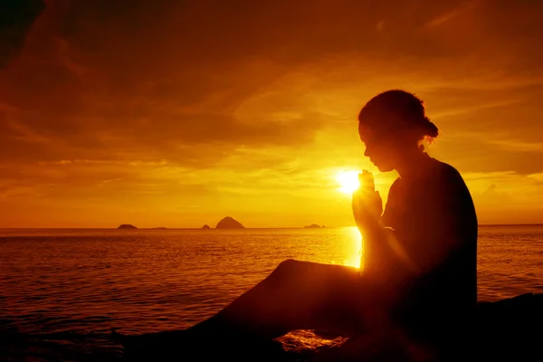 Jovem mulher rezando ao pôr do sol — Fotografia de Stock
