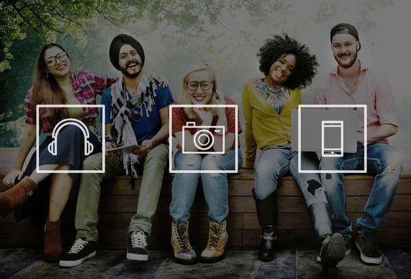 Friends sitting on bench with wireless devices — Stock Photo, Image