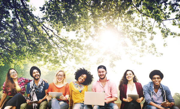 счастливые друзья сидят на скамейке с ноутбуком
