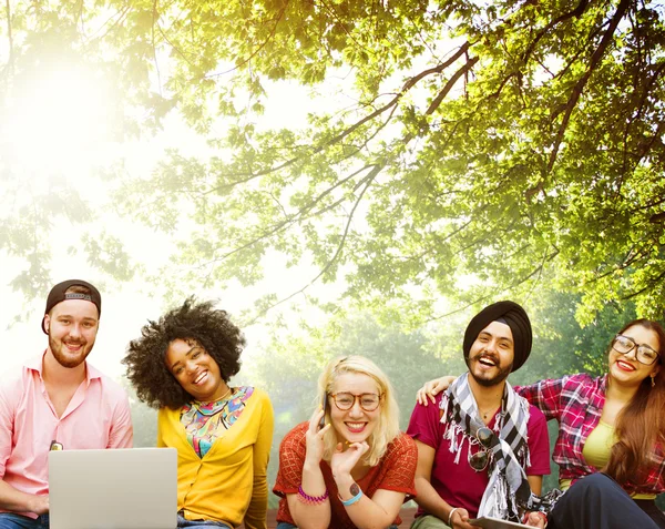 Happy friends sitting on bench with laptop — Stock Photo, Image