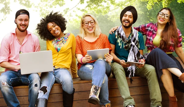 Amigos felizes sentados no banco com laptop — Fotografia de Stock