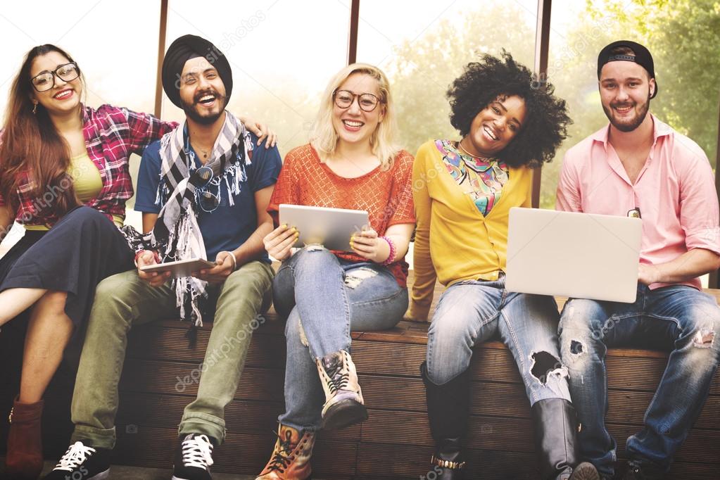 happy friends sitting on bench with laptop