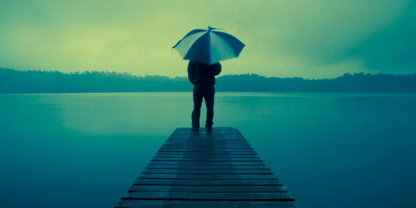 Uomo che tiene un ombrello al lago — Foto Stock