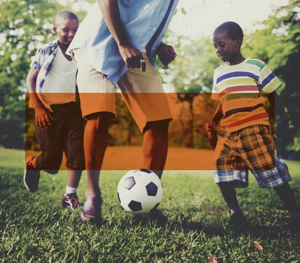 Far och söner som spelar fotboll i parken — Stockfoto