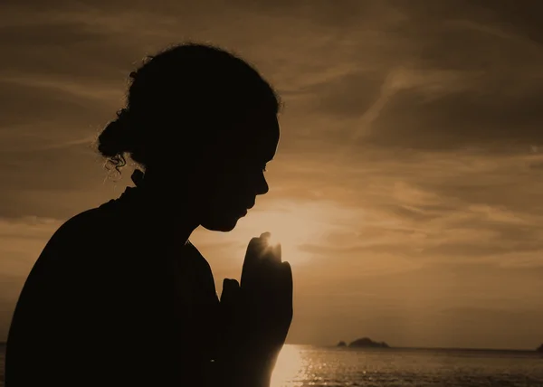 Jovem mulher rezando ao pôr do sol — Fotografia de Stock