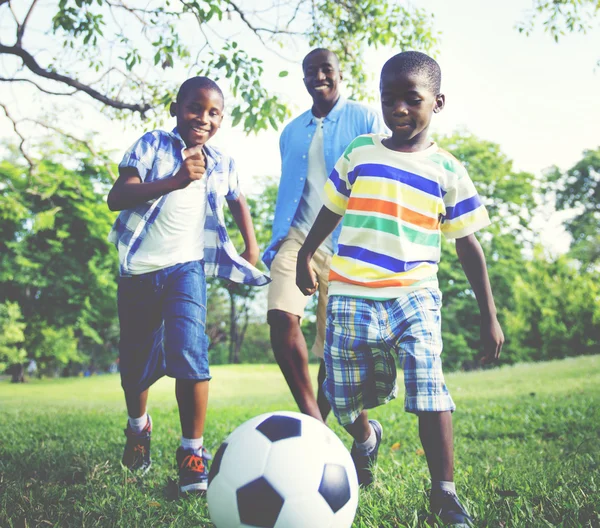 Pai e filhos jogando futebol no parque — Fotografia de Stock