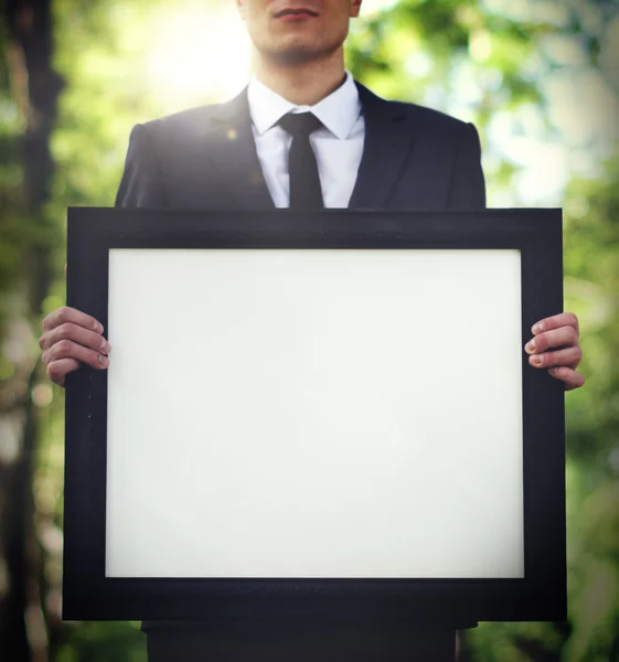 Empresario sosteniendo marco de imagen — Foto de Stock