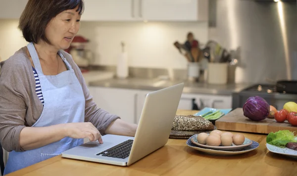 Домогосподарка шукає рецепт на ноутбуці — стокове фото