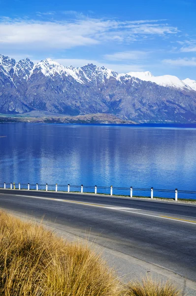 Strada con lago e catena montuosa — Foto Stock