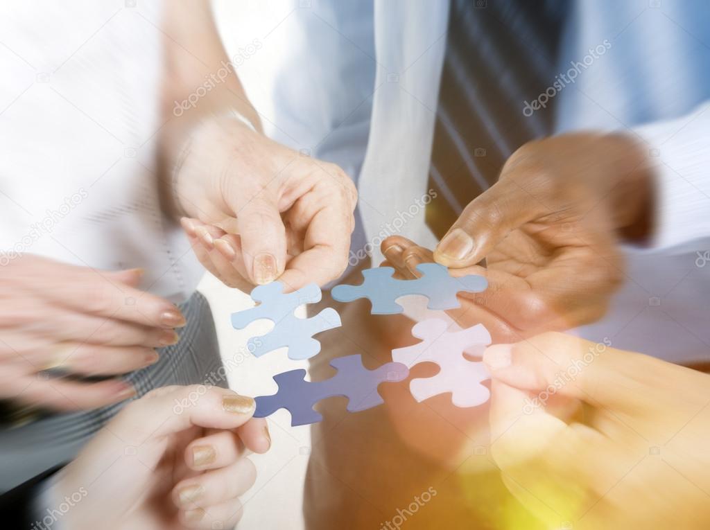 Business people hold puzzles