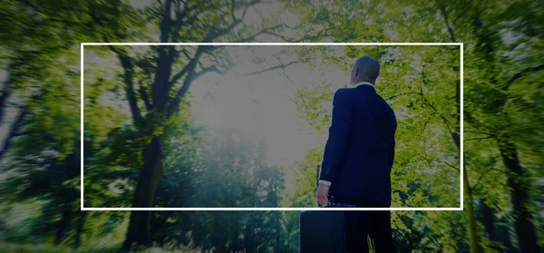 Businessman standing in green forest — Stock Photo, Image
