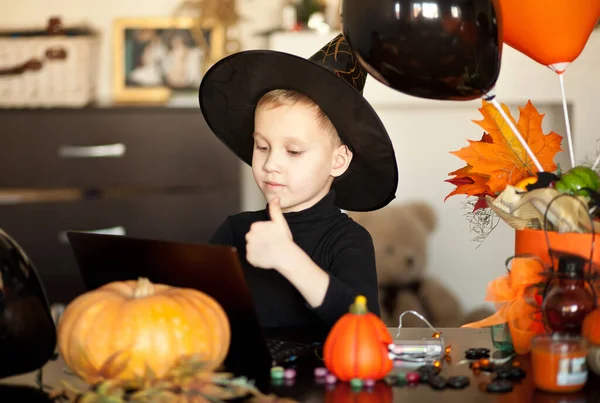 Zabawny chłopiec w stroju czarownicy na Halloween przy użyciu notebooka z tabletem cyfrowym. Przyjaciele online lub rodzice — Zdjęcie stockowe